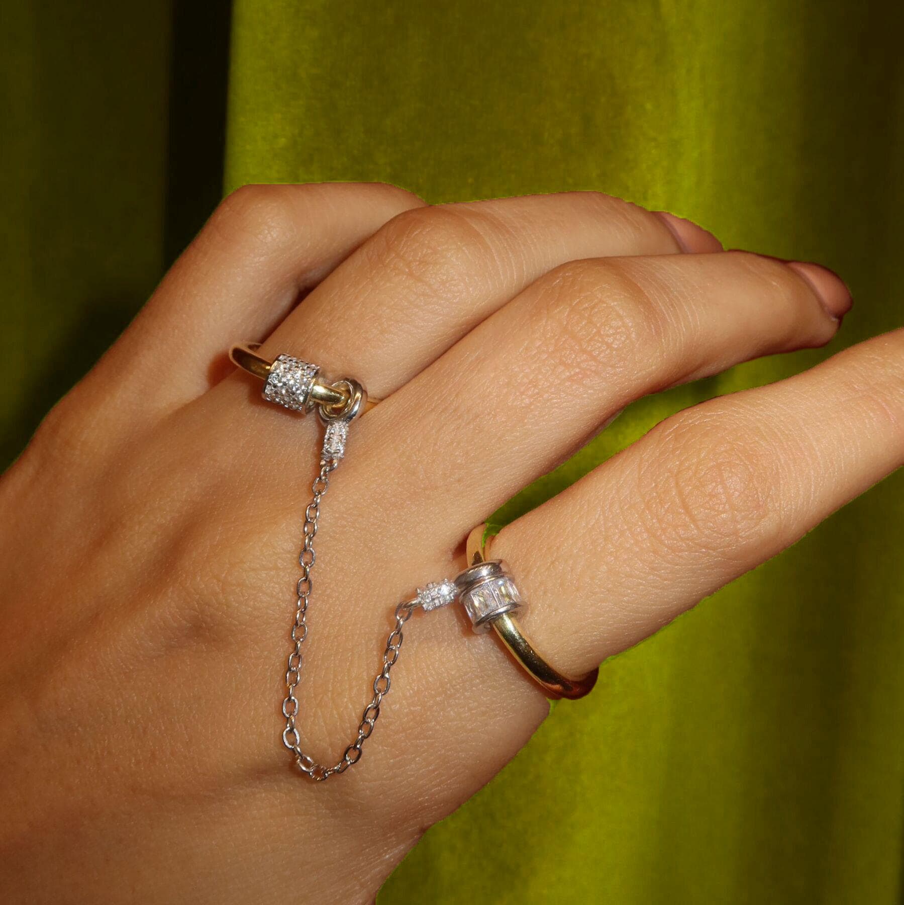 May include: Two gold rings with clear cubic zirconia stones. One ring has a chain attached to it.