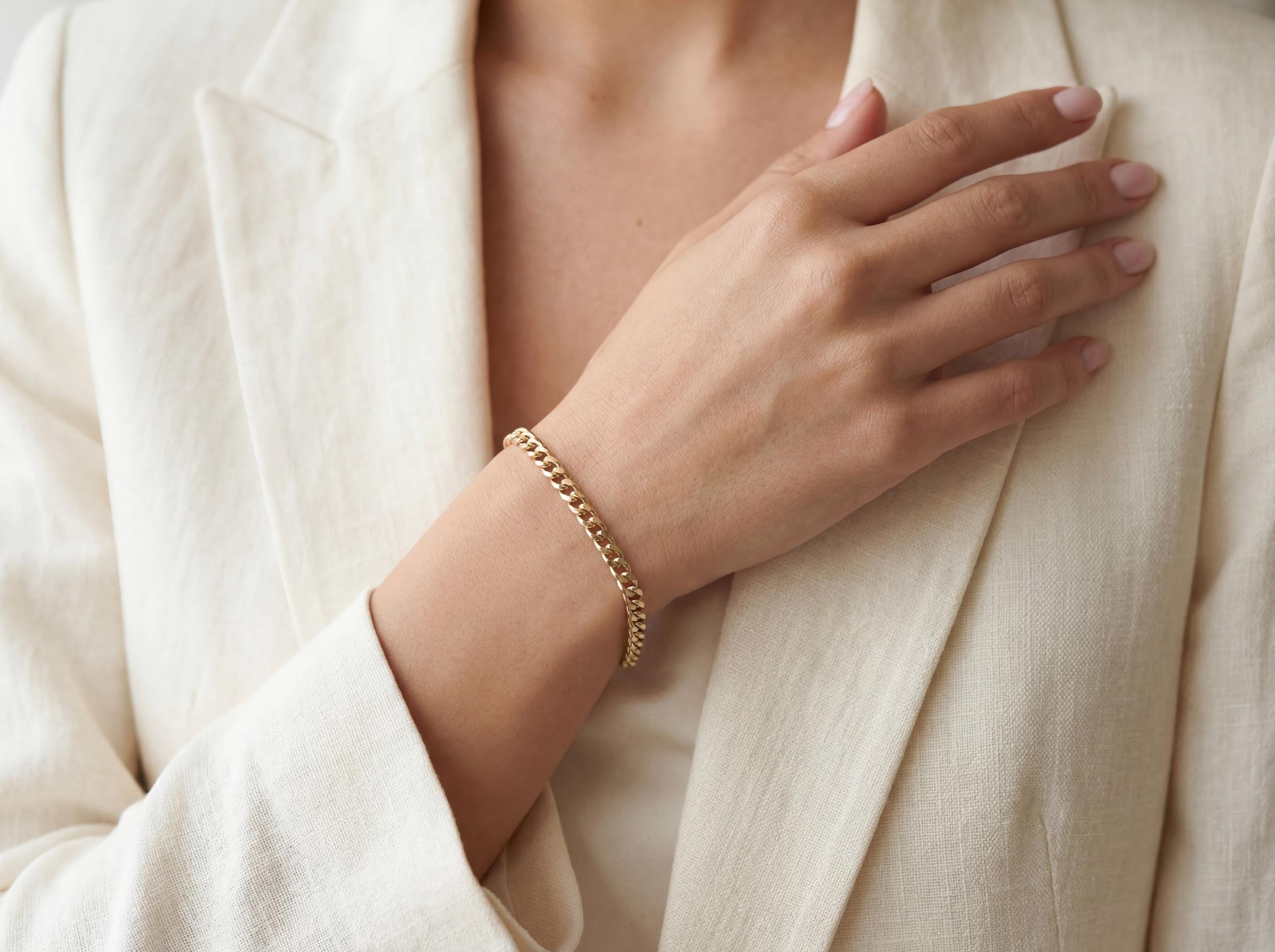 4mm cuban link bracelet solid 14k gold styled on wrist with neutral outfit, classic fine jewelry look
