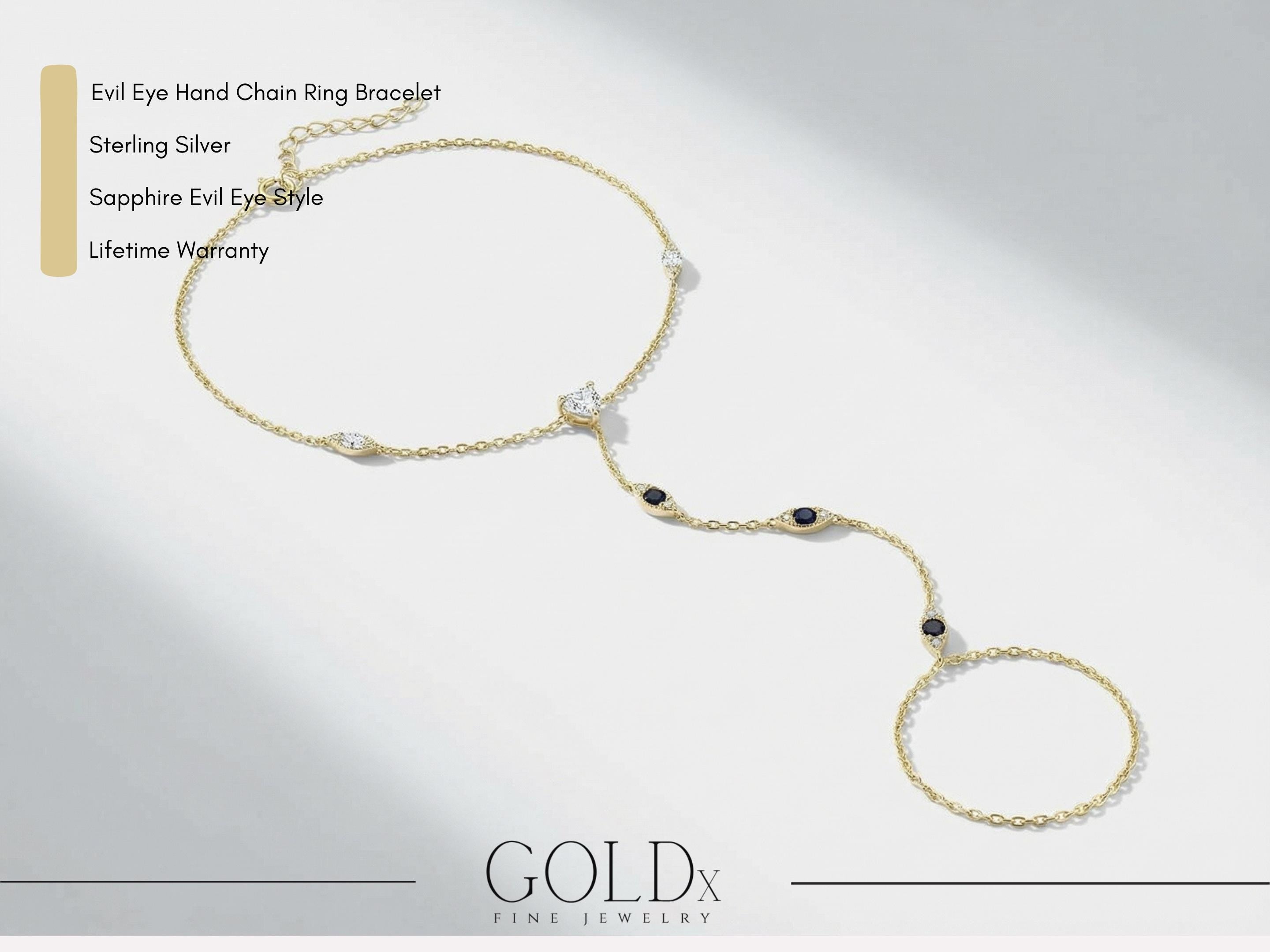 Minimal product image of 14k gold evil eye hand chain ring bracelet on light background with text describing sterling silver, sapphire style evil eye design and lifetime warranty, showing delicate chain and gemstone details.