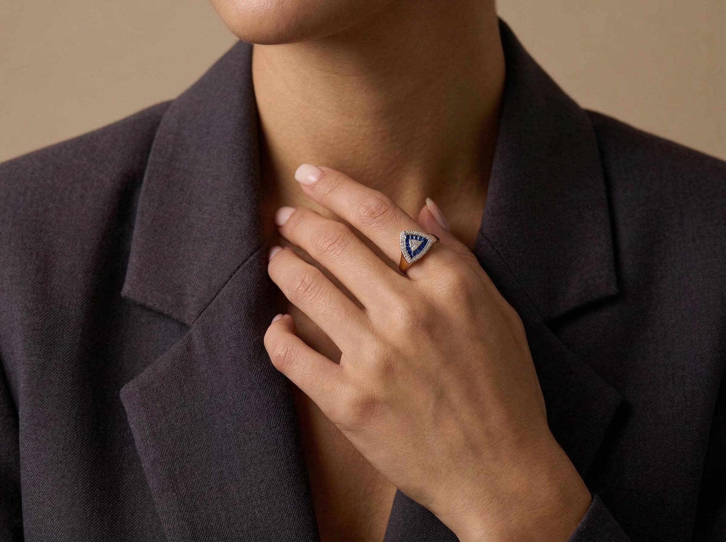 Sapphire baguette triangle ring worn on female hand, solid 14k gold geometric design with diamond halo detail. Natural pose showing size and appearance when worn.